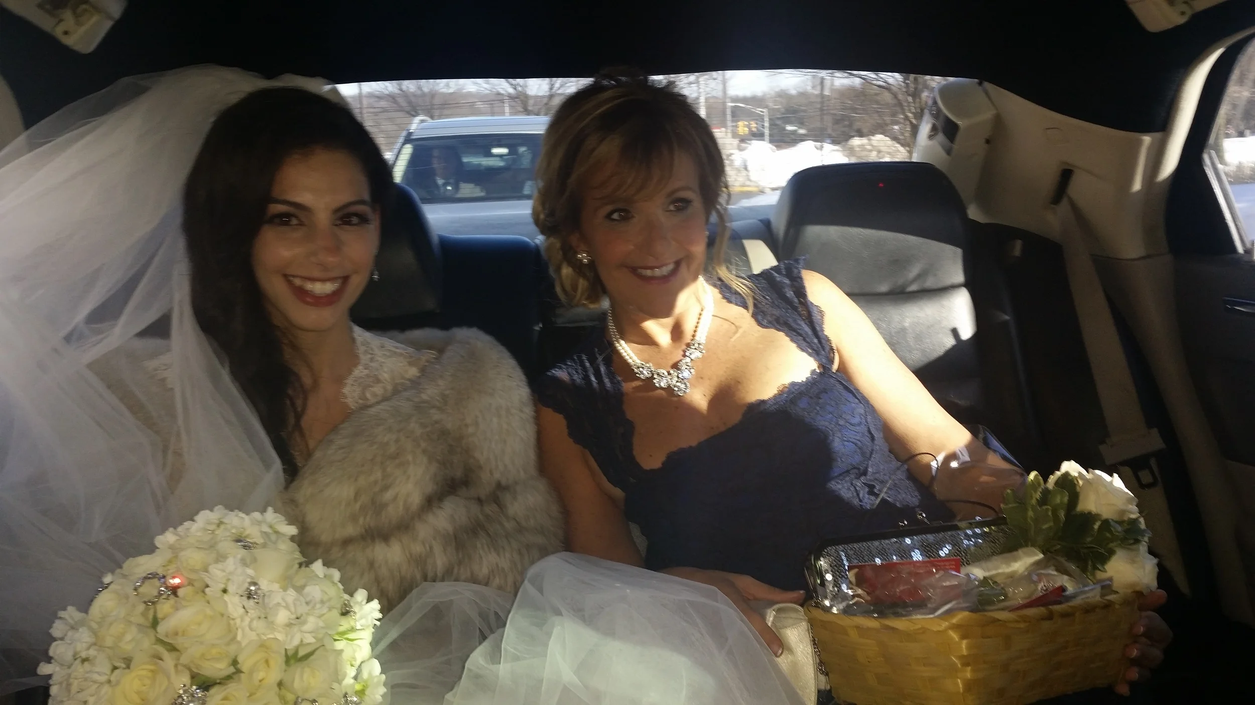 Bride seated in a car with the mother of the bride
