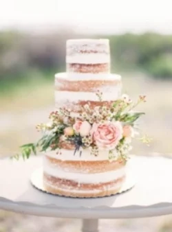 Naked wedding cake decorated with blush flowers and greenery