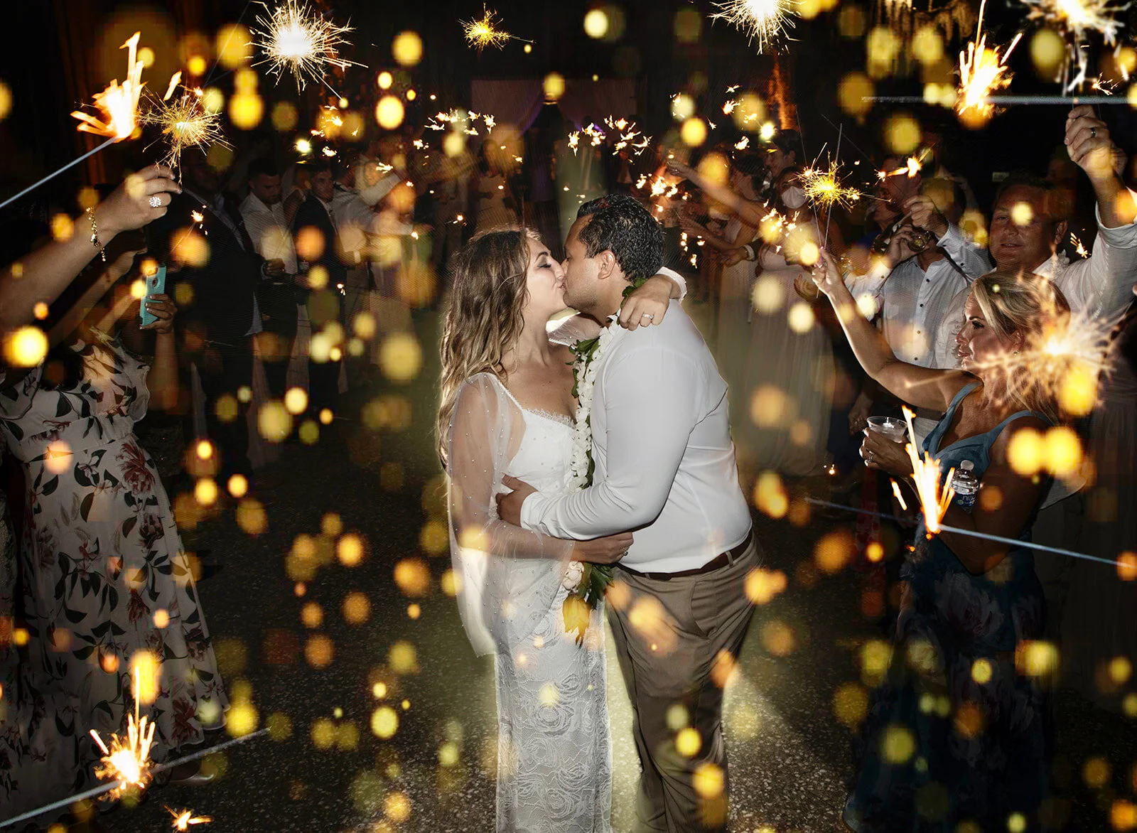 Newlyweds kissing during a sparkler exit