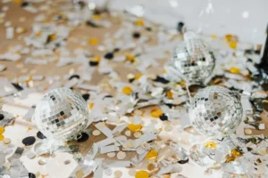 Mini disco balls scattered among gold and silver confetti