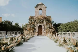 Outdoor wedding aisle leading to a rustic stone chapel