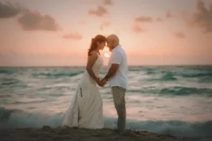 Newlyweds holding hands on a beach at sunset