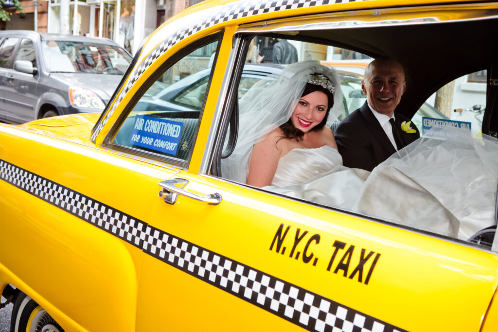 Bride and groom riding in a yellow New York City taxi