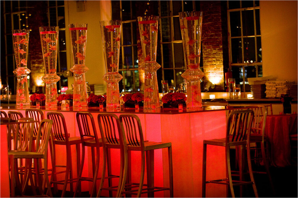 Illuminated bar setup with dramatic lighting and decor at an upscale corporate event.