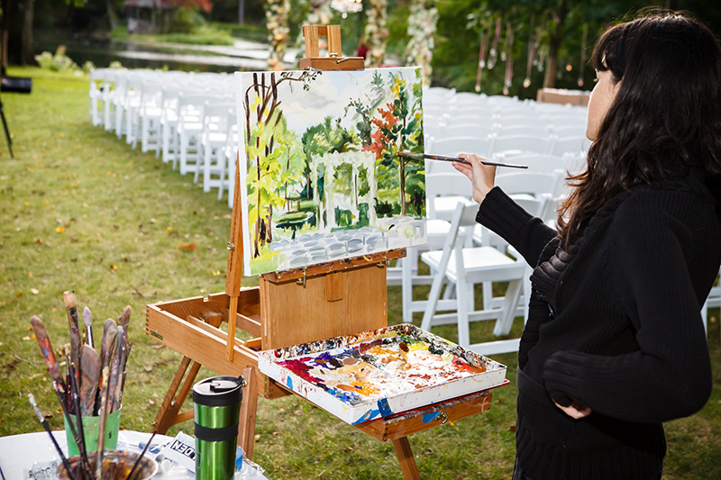 Live event artist painting an outdoor celebration scene during a private event.