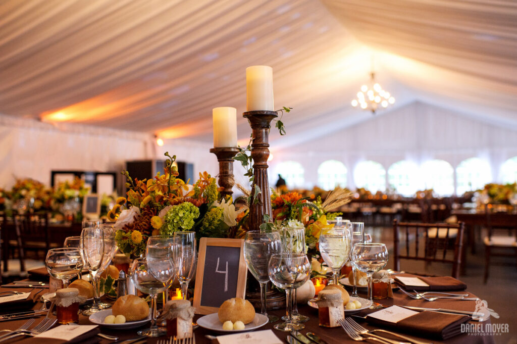 Elegant tented wedding reception with draped ceiling, candlelight, and autumn floral tablescape.