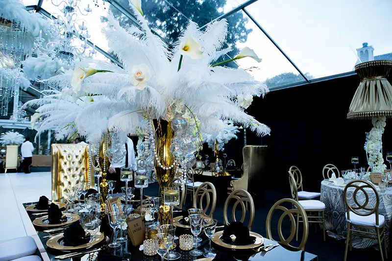 Elaborate private event tablescape with dramatic white feather centerpieces and elegant place settings.